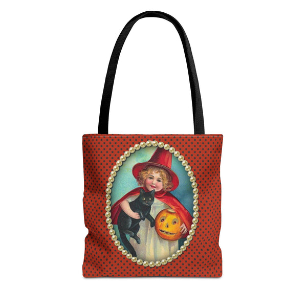 A Halloween tote bag featuring a vintage-style illustration of a young girl in a red witch costume holding a black cat and a jack-o-lantern, framed by pearls on a polka-dot orange background.