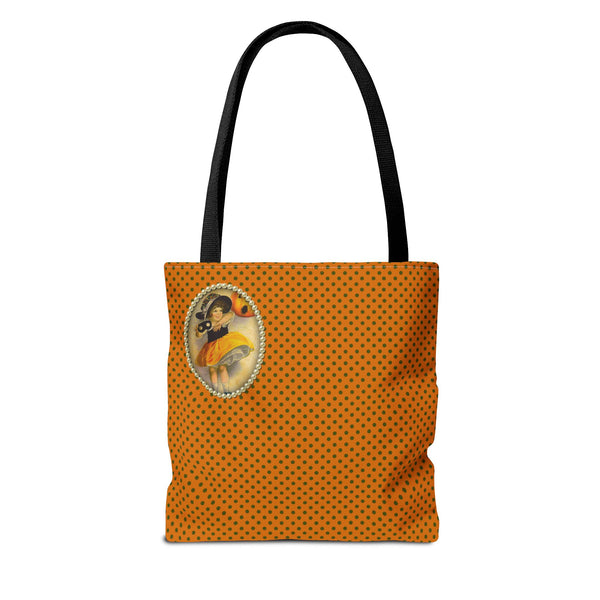 Back side of Halloween-themed tote bag with a vintage-inspired design, featuring a small illustration of a young girl in a witch costume framed with pearls on an orange polka dot background. The design is placed in the upper left corner of the bag.