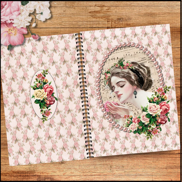 A spiral-bound notebook or journal laid open on a wooden surface, featuring a vintage floral pattern in pink and cream, with an oval portrait illustration of a woman surrounded by flowers on the right page and a matching floral oval on the left page.
