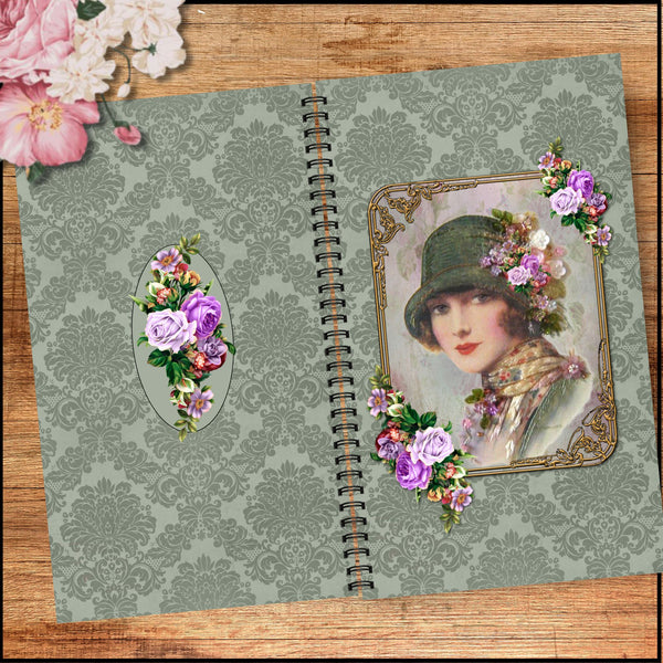 A vintage-style spiral-bound notebook or journal lies open on a wooden surface. The cover has a muted sage green damask pattern, floral oval and portrait decorations with purple flowers, and a black spiral binding.
