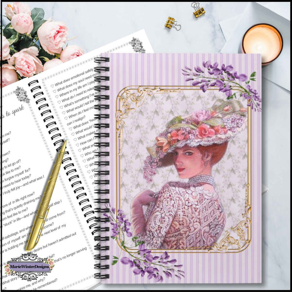 A spiral-bound journal or notebook cover featuring a vintage-style illustration of a woman in an ornate floral hat, set on a light marble-like surface with flowers, a candle, and a pen nearby.