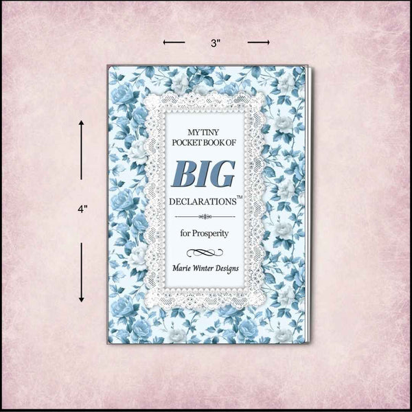 A pocket book with a blue floral border and a white lace-style center panel, shown on a pink textured background with dimension arrows indicating 3 inches wide by 4 inches tall. The title reads 'My Tiny Pocket Book of Big Declarations for Prosperity' by Marie Winter Designs.