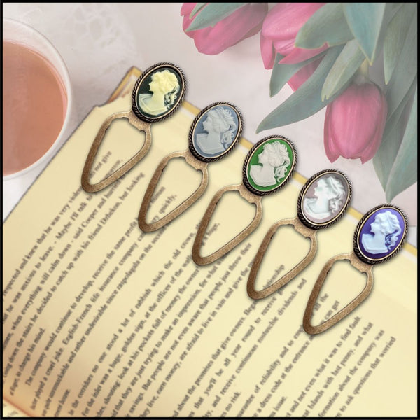 Vintage cameo bookmarks with antique bronze finish in assorted colors, displayed on an open book with pink tulips and tea.