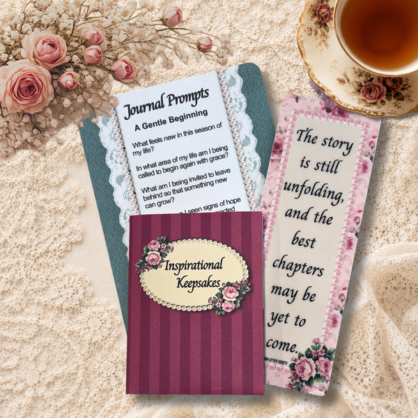 Inspirational keepsake folder displayed with a journal prompt card and floral bookmark on a cream lace background beside pink roses and a vintage teacup.