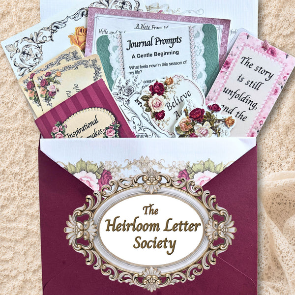 The Heirloom Letter Society vintage-inspired snail mail subscription featuring a burgundy envelope filled with encouraging letters, journal prompts, bookmarks, floral stickers, and heirloom-inspired paper keepsakes.