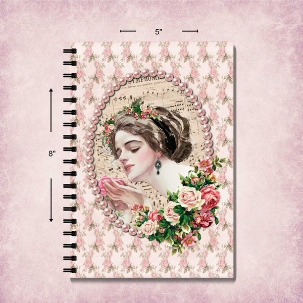 A spiral-bound notebook with a vintage-style floral cover design, shown on a pink textured background with dimension arrows indicating 5 inches wide by 8 inches tall.