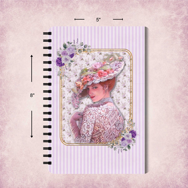 A spiral-bound notebook with a vintage-style illustration of a woman in a floral hat on a lavender striped cover, shown with dimension arrows indicating 8 by 5 inches on a textured pink background.