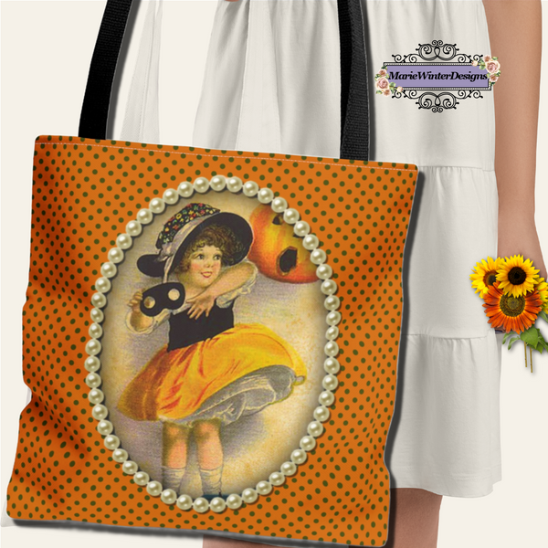 Person in a white dress holding a tote bag with a vintage-inspired Halloween design featuring a young girl in a witch costume, framed with pearls on an orange polka dot background. A small bouquet of sunflowers is in their hand,