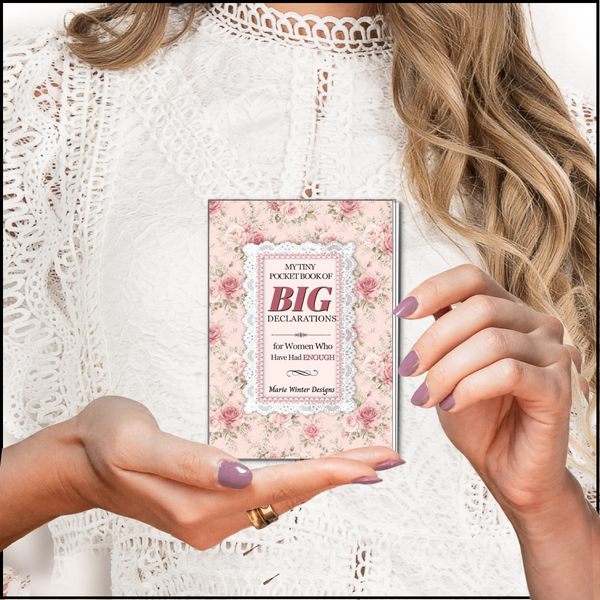 A woman in a white lace top holds a slim book titled "My Tiny List of Big Declarations" with a pink floral cover. The photo is styled as a close-up lifestyle shot with the woman's hands and hair visible.