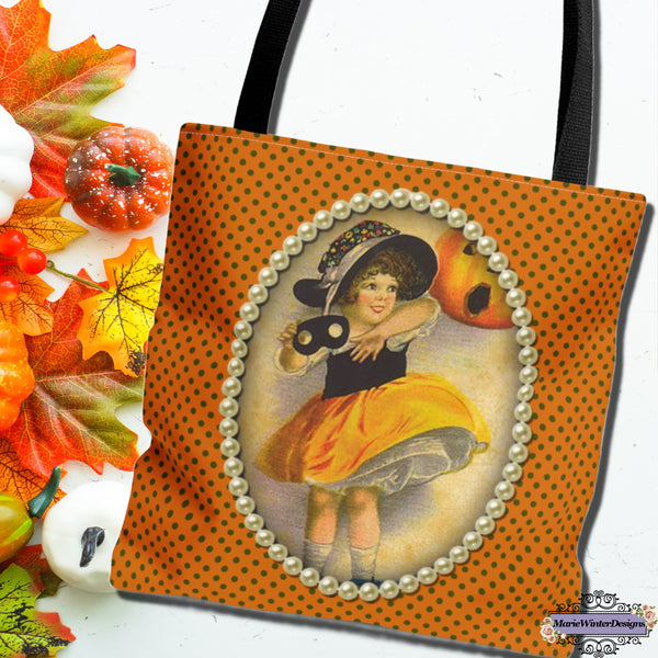 Vintage-inspired Halloween tote bag featuring an illustration of a young girl in a witch costume, framed with pearls on a polka dot orange background, with fall leaves and pupmpkins nearby