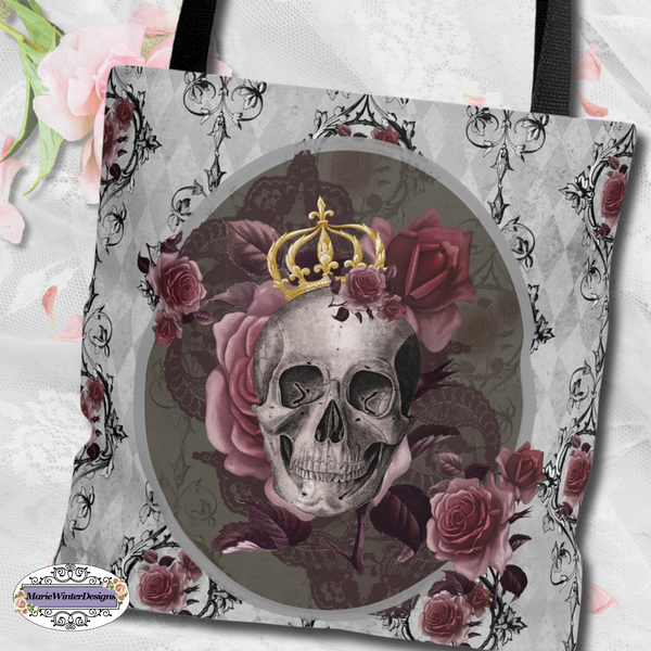 Tote bag with black handle and design of a gray skull with gold crown and roses on a gray background with back scroll lines and burgundy flowers