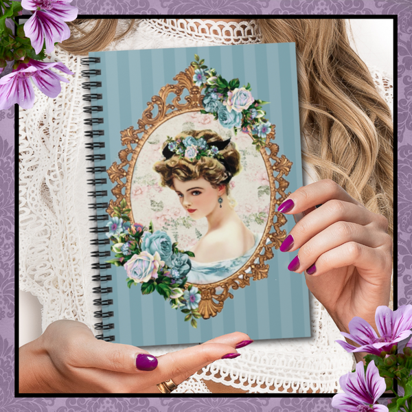Woman with polished nails holding a Spiral Bound Notebook/Journal featuring a Lovely Victorian image of a Harrison Fisher Illustration surrounded with a gold frame accented with a cluster of blue flowers on a blue striped background.
