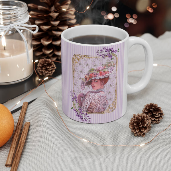 Ceramic Mug with Elegant Early 1900s Vintage Woman wearing  a Purple Lace Dress, Large Floral Hat Purple on Striped Background and White Handle on a desk with a candle behind and 2 small pine cones in front.